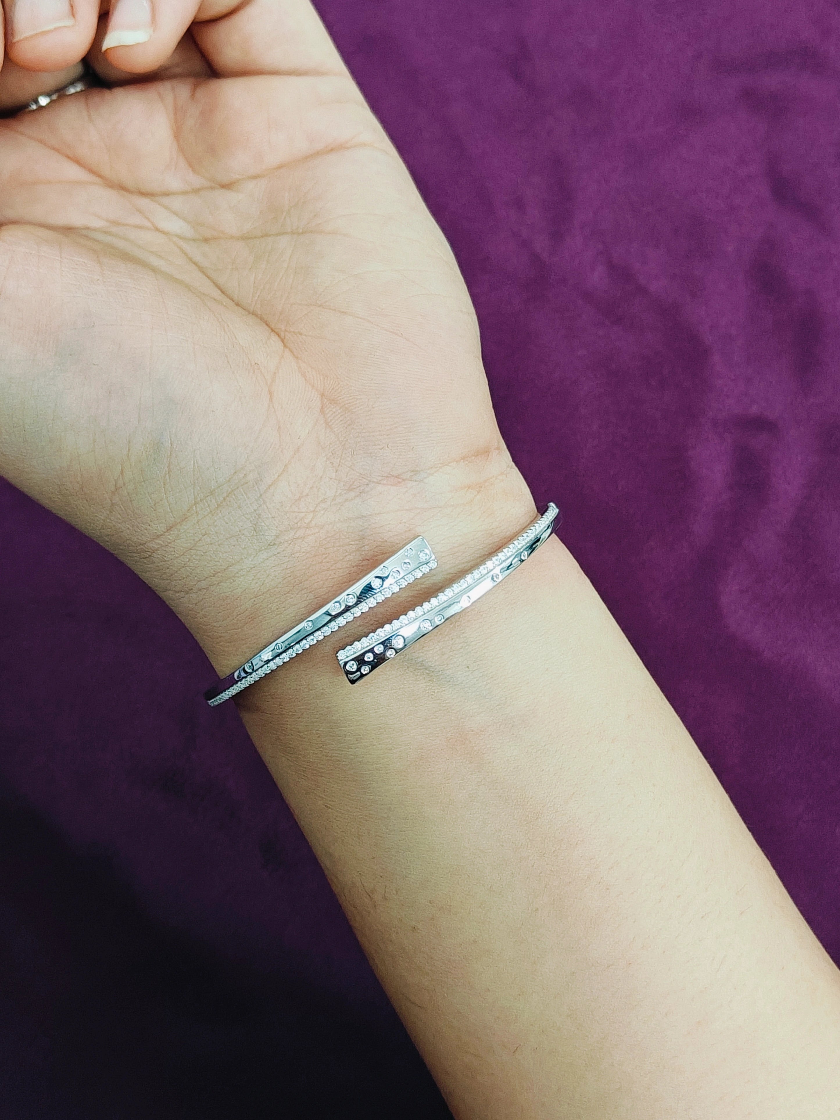 Silver bracelet on a wrist with a purple background